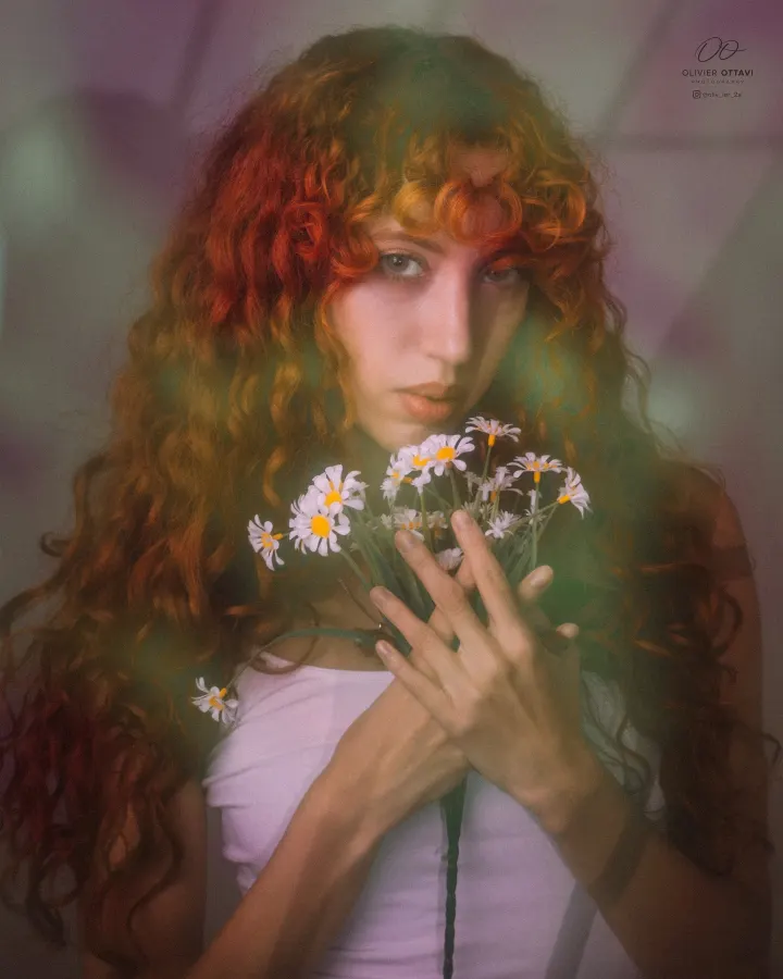 Dreamlike editorial portrait of a red-haired model holding wild flowers